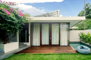 A modern house with a glass door, a small pool, and a garden.