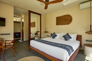 A hotel room with a large bed, wooden furniture, a television, and decorative wall art.