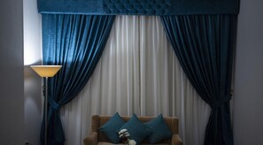 A room with a sofa, a lamp, and blue curtains. - Rehana Resort (Cairo)