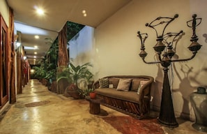 A hallway with a sofa, potted plants, and a decorative lamp. - Corazon de Jade Tulum (Tulum)