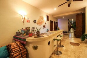 Un espace bar comprenant un comptoir, des tabourets et des éléments de décoration murale, notamment une horloge et un motif en forme de cœur.
