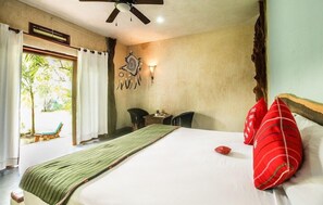 A hotel room with a bed, a ceiling fan, a window with curtains, a small table, and a chair. - Corazon de Jade Tulum (Tulum)