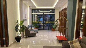 A modern hotel lobby with a reception desk, seating area, and a large glass door leading to the entrance. - Sky Hotel Aqaba (Aqaba)