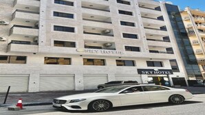 A multi-story hotel with balconies, a car parked in front, and a clear sky. - Sky Hotel Aqaba (Aqaba)