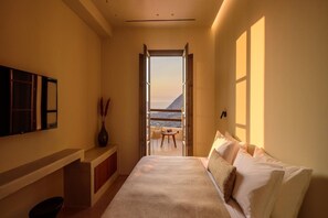 Une chambre à coucher comprenant un lit, une table de chevet, un miroir et donnant sur un balcon avec une table et des chaises.
