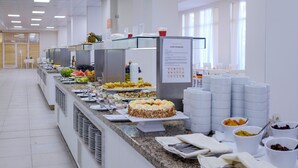 Ένας μπουφές με διάφορα είδη φαγητού, μια τούρτα και μια πινακίδα με πληροφορίες σχετικά με αλλεργιογόνα.