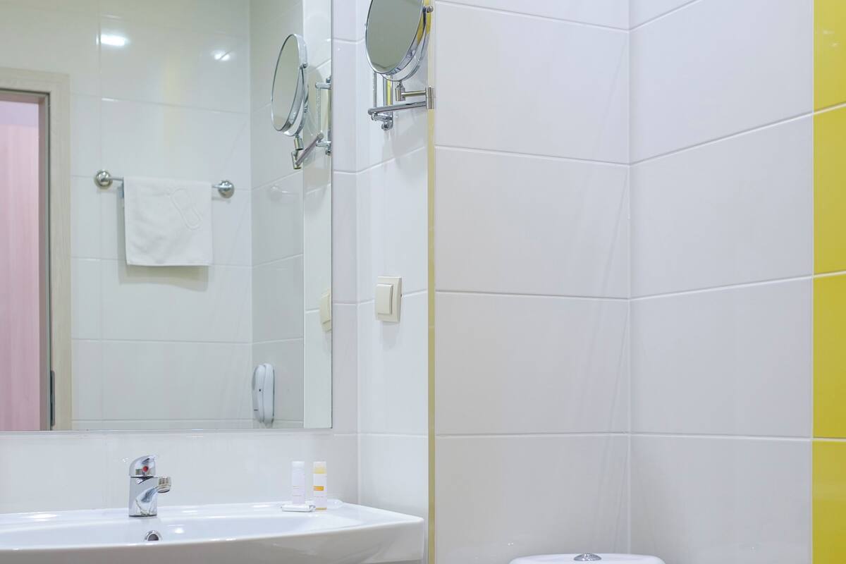 A bathroom with a white sink, mirror, and toilet.