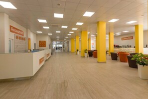 A reception area with a reception desk, a lobby bar, and yellow pillars. - Hotel Garden Nevis (Nessebar)