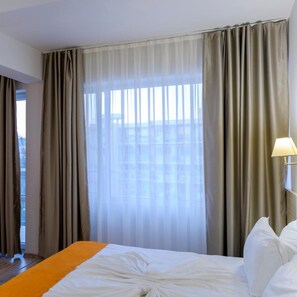 A hotel room with a bed, curtains, a window, and a lamp. - Hotel Garden Nevis (Nessebar)