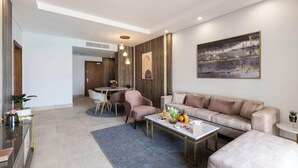 A modern living room with a sofa, coffee table, and dining area. - Gewan Resort New Alamein (El Alamein)