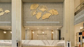 A reception area with a marble counter, a wall-mounted reception desk, and a decorative wall with leaf-like patterns. - Gewan Resort New Alamein (El Alamein)