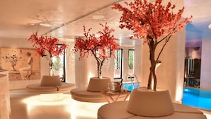 A modern lounge area with round seating, decorative trees, and a pool view. - Maritim Marina Bay Resort & Casino (Vlorë)