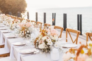 A long table set for a wedding with floral centerpieces, white tablecloths, and wooden chairs. - Maritim Marina Bay Resort & Casino (Vlorë)