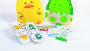 Two plush toys, one yellow and one green, with accompanying items like a map, a toy train, and a sponge. - Apa Hotel (Tokyo)