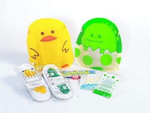 Two plush toys, a yellow duck and a green monster, along with some packaged items. - Apa Hotel (Tokyo)