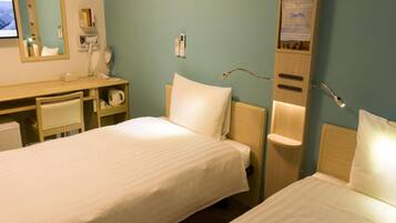A hotel room with two beds, a desk, a mirror, a phone, and a wall-mounted light fixture.