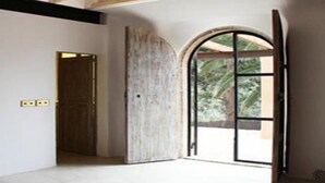 A room with a large arched window, a wooden door, and a concrete wall. - Dream of Zanzibar (Uroa)