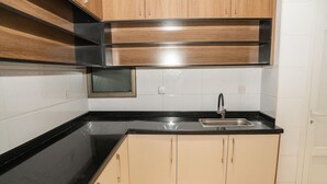 A kitchen with black countertops, wooden cabinets, and a stainless steel sink. - Swiss Spirit Hotel and Suites Dammam (Dammam)