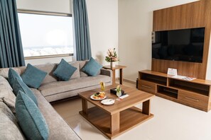 Un salon moderne avec un canapé, une table basse, un téléviseur et un meuble TV en bois.