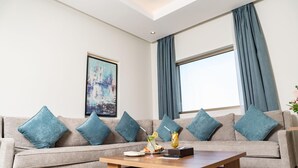 A modern living room with a grey sofa, blue cushions, a wooden coffee table, and a framed abstract painting. - Swiss Spirit Hotel and Suites Dammam (Dammam)