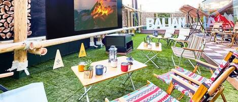 An outdoor patio with a large flat-screen TV, outdoor seating, and a 'BALIAN' sign.