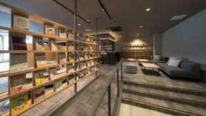 A modern library with bookshelves, a sofa, and a staircase. - Book Hotel Kyotokujo (Otsu)