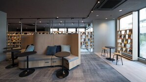 A modern library with a seating area, bookshelves, and tables. - Book Hotel Kyotokujo (Otsu)