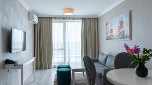 Ein modernes Hotelzimmer mit Sofa, Esstisch und einem Bild an der Wand.