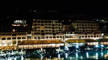 A waterfront hotel with multiple buildings, a covered walkway, and a pool area.