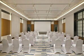 A conference room with rows of white chairs, a projector screen, and a patterned carpet. - Intercontinental ABU Dhabi Residence (Abu Dhabi)