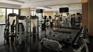 A gym with various exercise equipment, a large mirror, and a television. - Intercontinental ABU Dhabi Residence (Abu Dhabi)