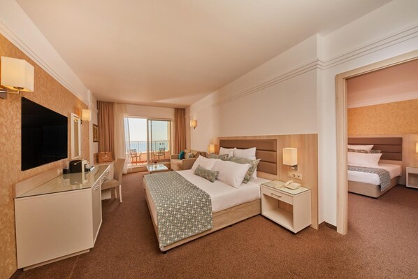 A hotel room with a bed, bedside tables, a desk, a TV, and a balcony view.