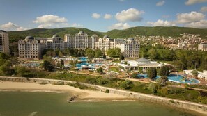 Un complexe hôtelier comprenant plusieurs bâtiments, une grande piscine et une plage.