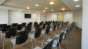 A conference room with rows of chairs, a flat-screen TV mounted on the wall, and a door at the far end. - Alua Sunny Beach Resort & Spa (Nessebar)