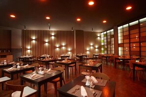 A restaurant with multiple tables and chairs, warm lighting, and a modern interior design.