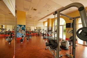A spacious gym with various exercise equipment, large windows, and a mirrored wall. - Dreams Sunny Beach Resort SPA (Nessebar)