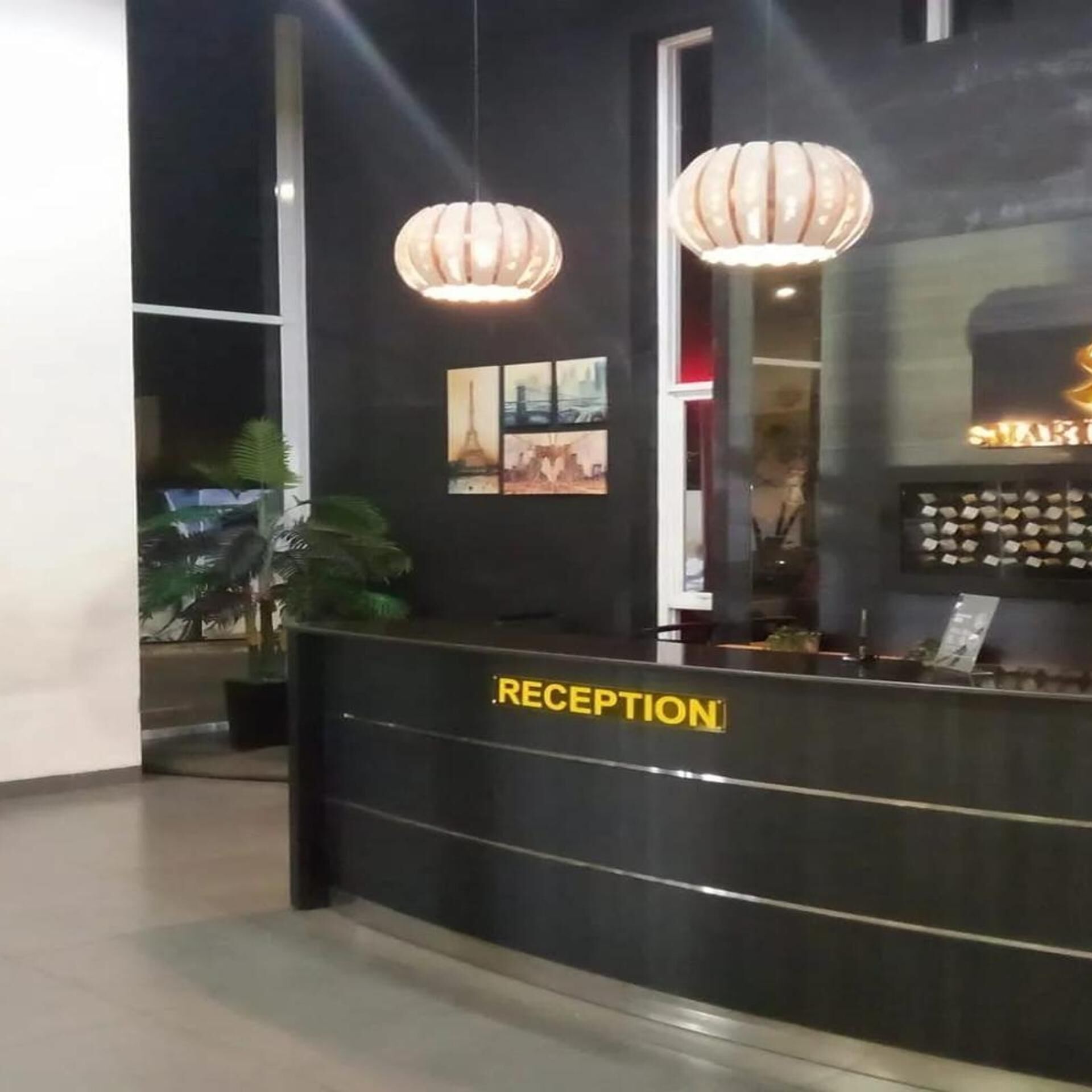 A reception desk with a 'RECEPTION' sign, two pendant lights, and framed pictures on the wall.