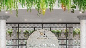 Un comptoir d’accueil surmonté d’un plateau en marbre, un homme debout derrière, et une enseigne indiquant : « Réception du Siena Premium Retreat ».