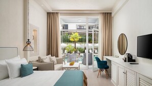 Une chambre d’hôtel équipée d’un lit, d’un bureau, d’une télévision et d’un balcon avec du mobilier d’extérieur.