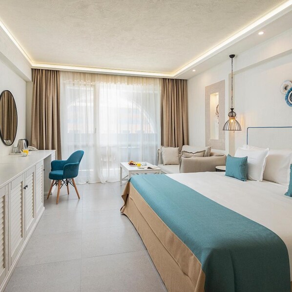 A hotel room with a bed, a desk, a chair, a sofa, and a window with curtains. - Siena Premium Retreat (Tsarevo)