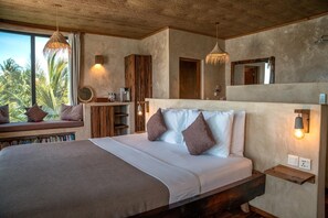 Un dormitorio con una cama grande, un asiento junto a la ventana, un cabecero de madera y vistas a palmeras.
