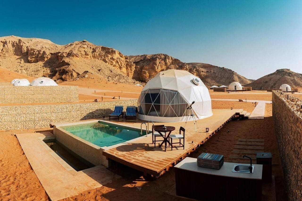 A desert resort with a swimming pool, outdoor seating, and dome-shaped accommodations.