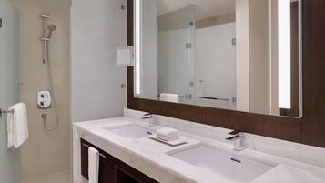 Une salle de bain moderne avec deux lavabos, un grand miroir et une douche.