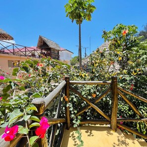 Eine Holzbrücke mit Metallgeländer, umgeben von üppiger Vegetation und blühenden Pflanzen.