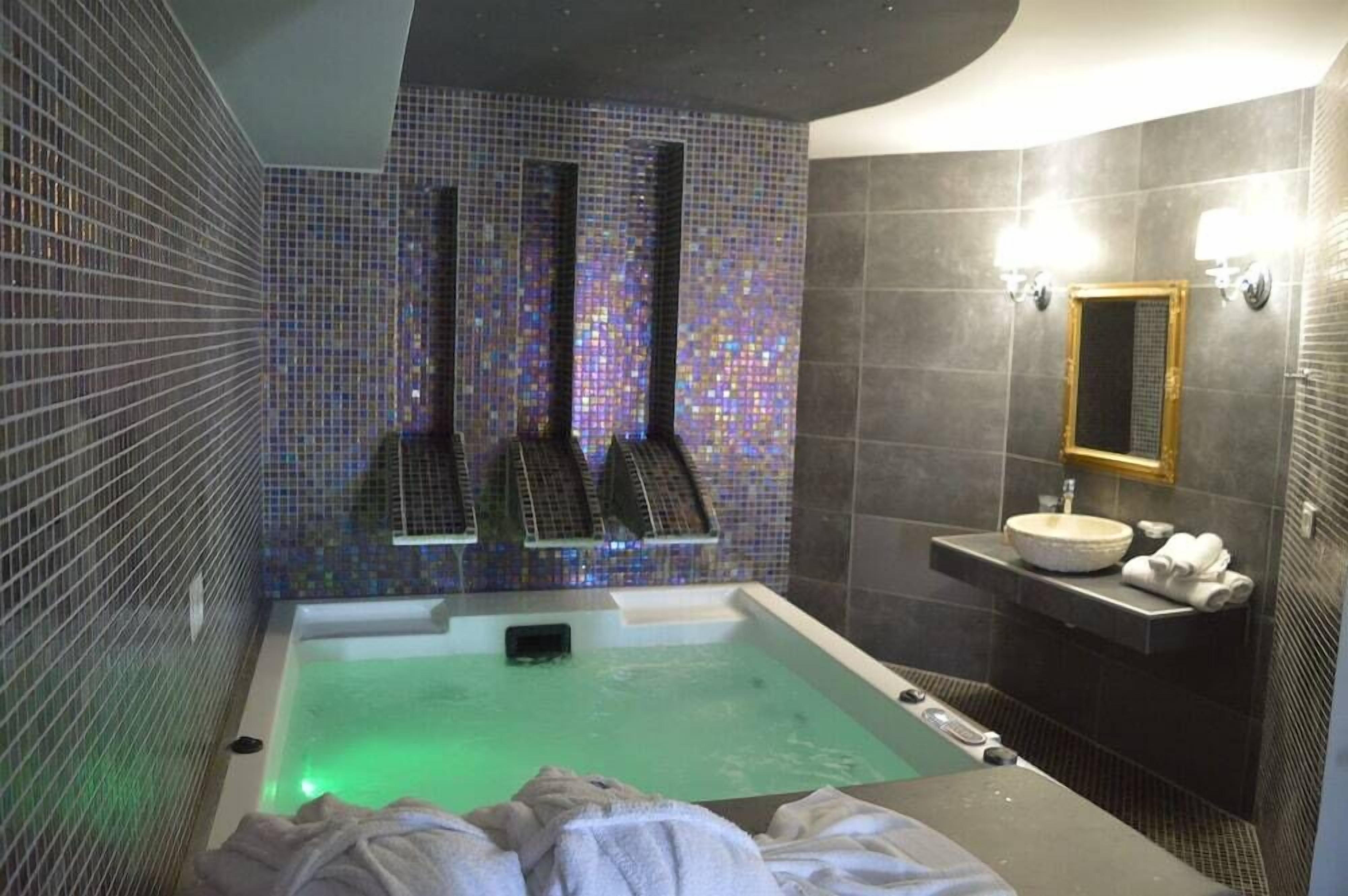 Un baño moderno con una bañera grande, un lavamanos pequeño y un espejo.