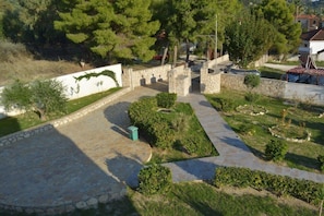 Un patio con senderos de piedra, césped verde y árboles.