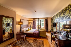 A bedroom with a large bed, a desk, a chair, a mirror, and a window with curtains. - The Bears Paw Inn (Sandbach)