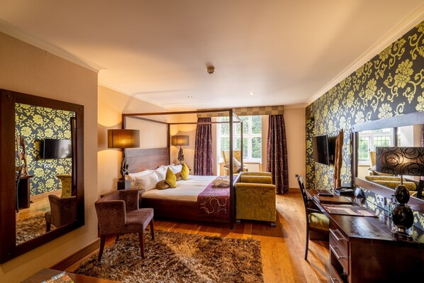 A bedroom with a large bed, a desk, a chair, a mirror, and a window with curtains. - The Bears Paw Inn (Sandbach)