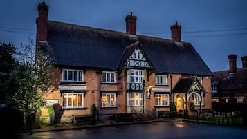 Edificio in mattoni tradizionale con un cartello che indica il pub 'The Bear's Head', un ingresso visibile e una panchina all'esterno.