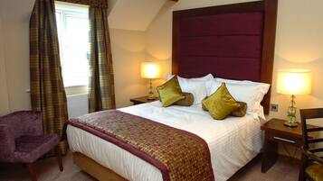 A hotel room with a large bed, two bedside lamps, a chair, and a window with curtains.